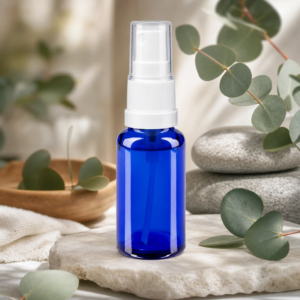 Frasco pulverizador azul de 20 ml de cristal de farmacia con dosificador blanco, sobre fondo de piedra natural y eucalipto