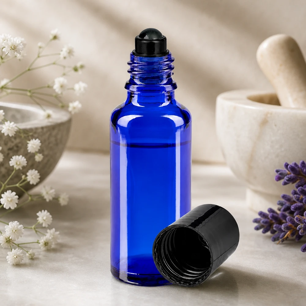 Botella de farmacia azul 30ml tapón roll-on negro Frasco de farmacia azul de 30 ml con aplicador de bola rodante negro, junto a una lavanda y un mortero