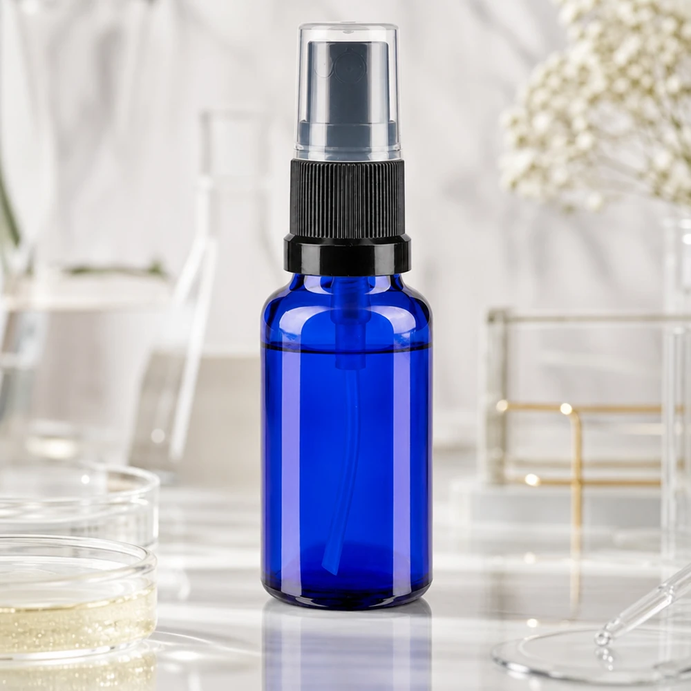 Botella pulverizadora de laboratorio azul de 20 ml con pulverizador negro sobre fondo de mármol blanco