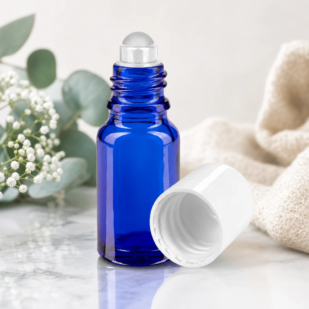 Botella de farmacia azul 10ml tapón roll-on blanco Frasco de farmacia con aplicador de bola de 10 ml, de color azul cobalto, con una bola de cristal transparente sobre fondo de mármol