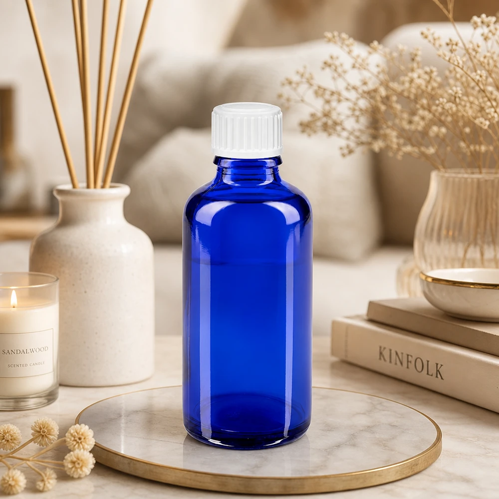 Frasco de farmacia de 50 ml, de color azul cobalto, con tapón estándar blanco, sobre una bandeja de mármol