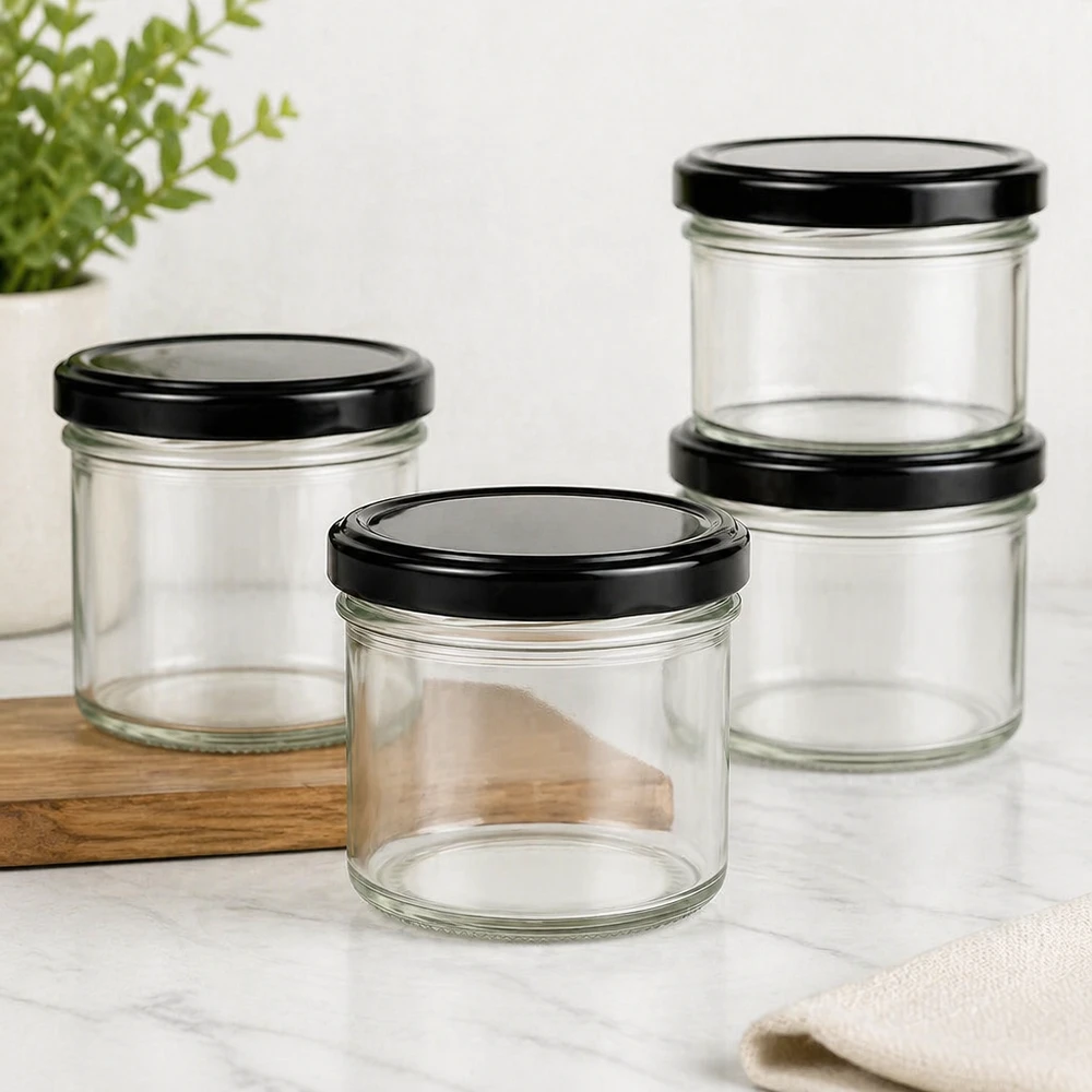 Vasos de 125ml con tapa BasicSeal negro UNiTWIST Cuatro vasos de 125 ml con tapa negra BasicSeal apilados sobre tabla de madera y mesa de mármol decoración de cocina