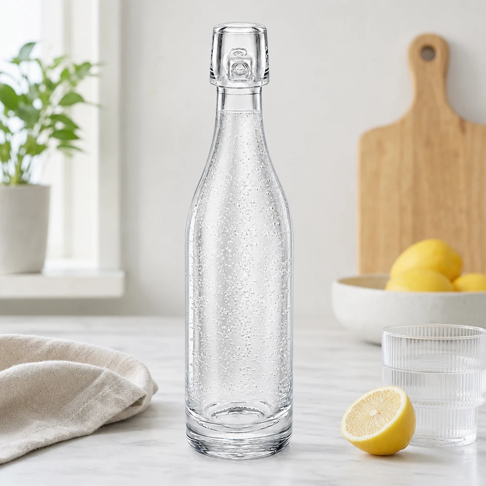 Botella de cristal de 50ml sin tapón basculante UNiTWIST Botella de cristal de 50 ml UNiTWIST llena de agua con gas en cocina moderna junto a limones y vasos encimera blanca