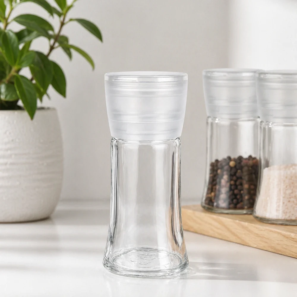 Frasco de especias vacío de 95 ml con molinillo blanco Vario junto a granos de pimienta y sal sobre una tabla de madera