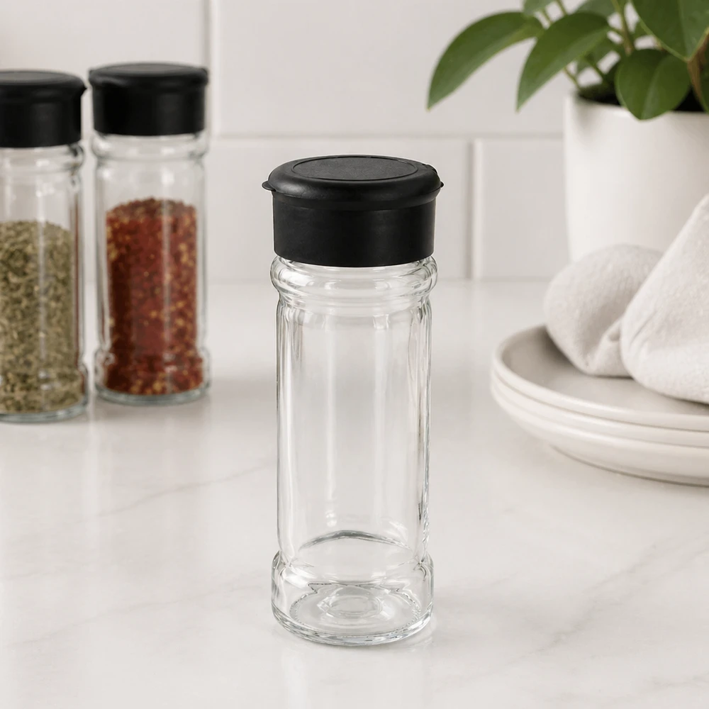 Frasco para sal y especias de 100 ml con dosificador, color negro Pequeño salero de cristal de 100 ml con tapa negra sobre una base de mármol blanco