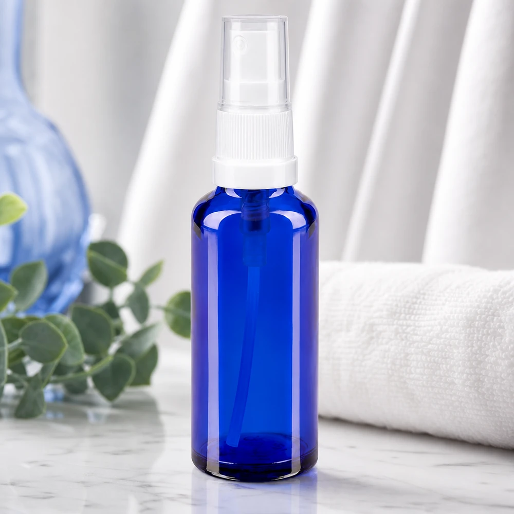 Vaso pulverizador de color azul cobalto, fabricado en vidrio de farmacia, con tapón transparente sobre una base de mármol