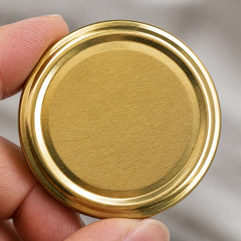 Primer plano de una tapa metálica dorada TO66 UNiTWIST BioSeal, de forma redonda y superficie texturizada