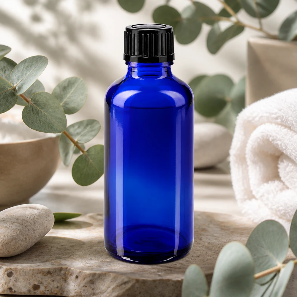 Frasco de farmacia azul de cristal de 50 ml con tapón de rosca negro, sobre una piedra natural con aroma a eucalipto