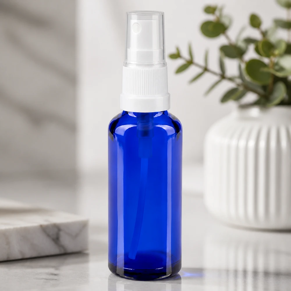 Botella de farmacia azul 30ml pulverizador blanco Frasco de farmacia azul de 30 ml con pulverizador blanco sobre un fondo de mármol blanco