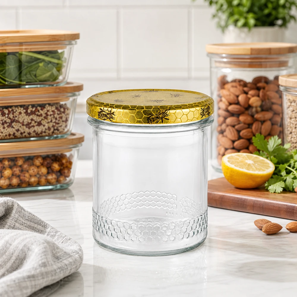 Tarro de miel de 400 ml con tapa de panal dorada sobre la encimera de la cocina, tarros de almacenamiento con frutos secos al fondo